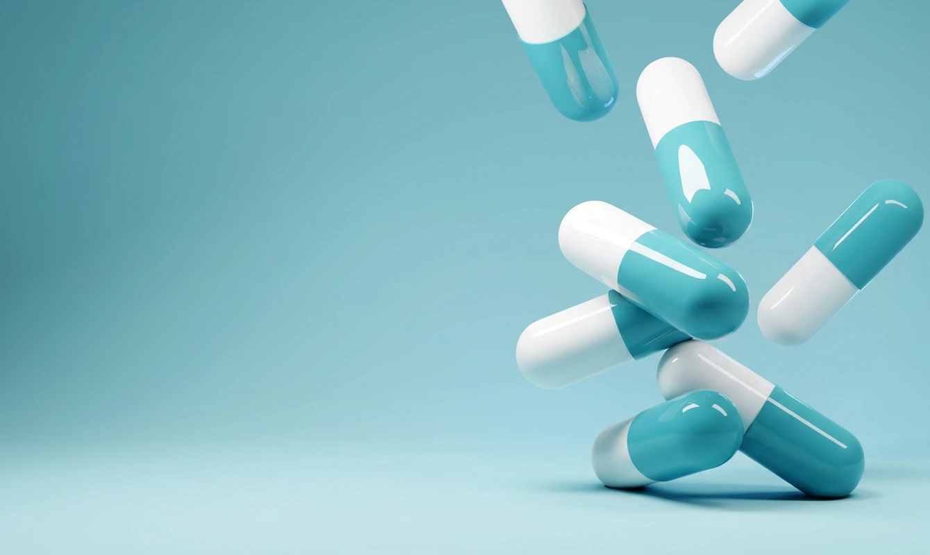 Blue and white medicinal capsules floating against a soft blue background.